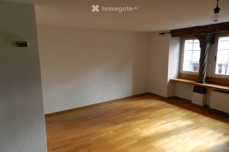 Empty room with wooden flooring, white walls, and two windows with wooden sills. No furniture or equipment present.