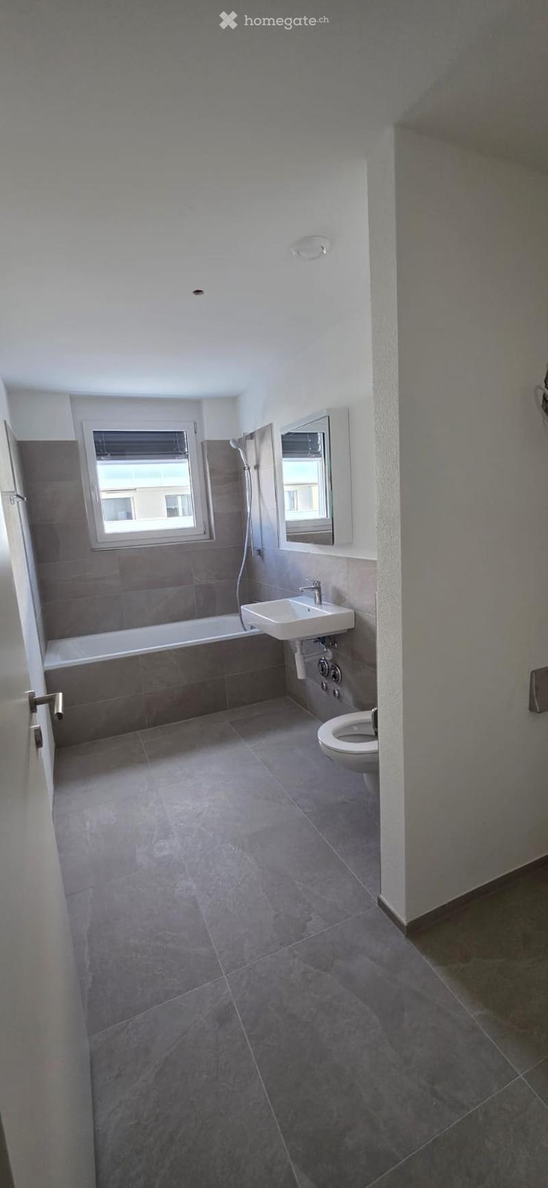 Bathroom with bathtub, sink, toilet, and shower area. Tiled floor and walls.