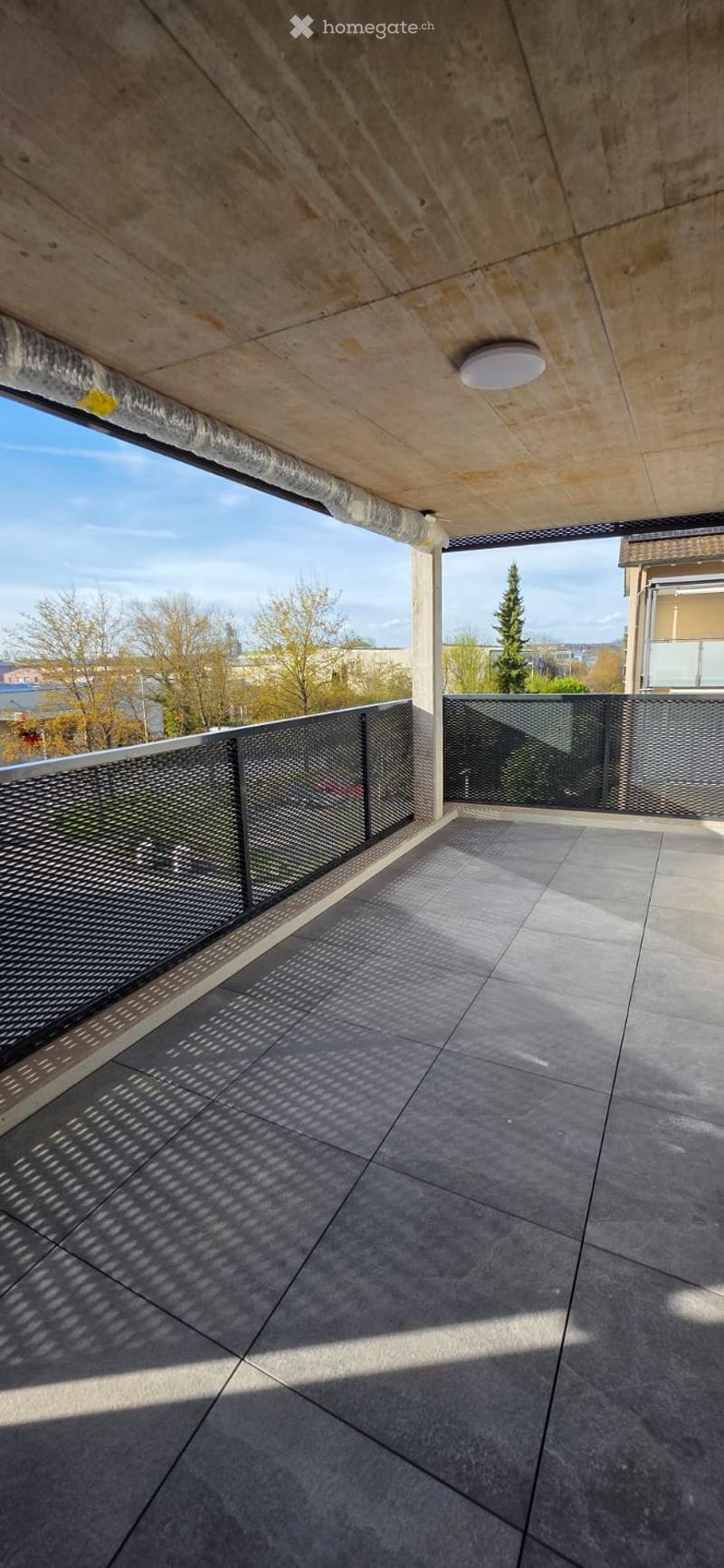 Empty balcony with tiled floor, metal railings, and a ceiling light.