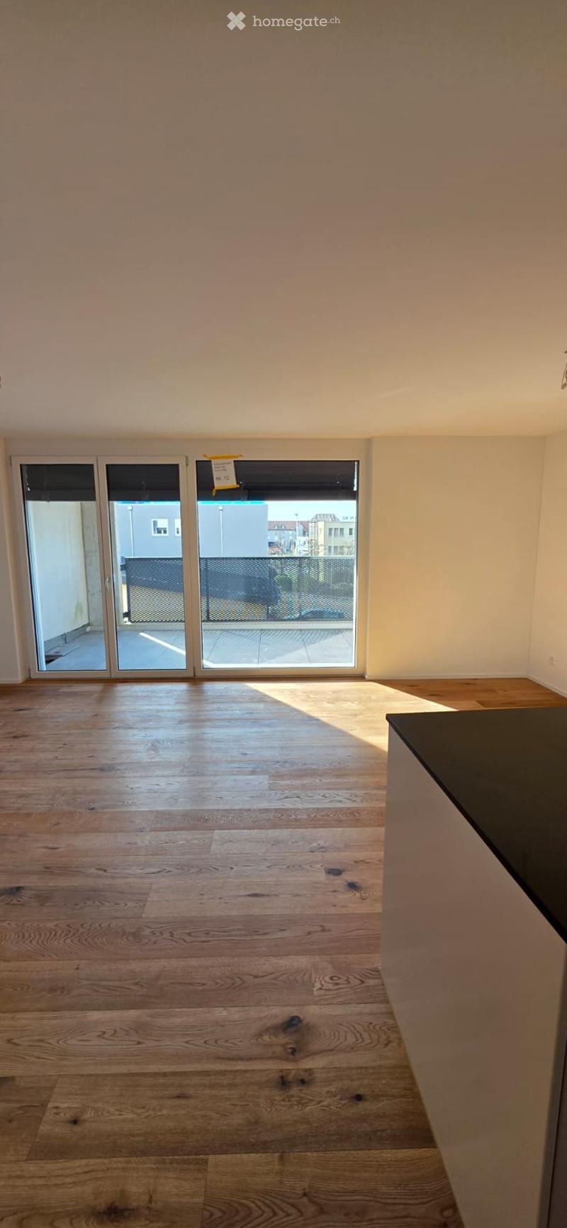 Empty room with wooden floors, large windows, and a balcony. No furniture or equipment.