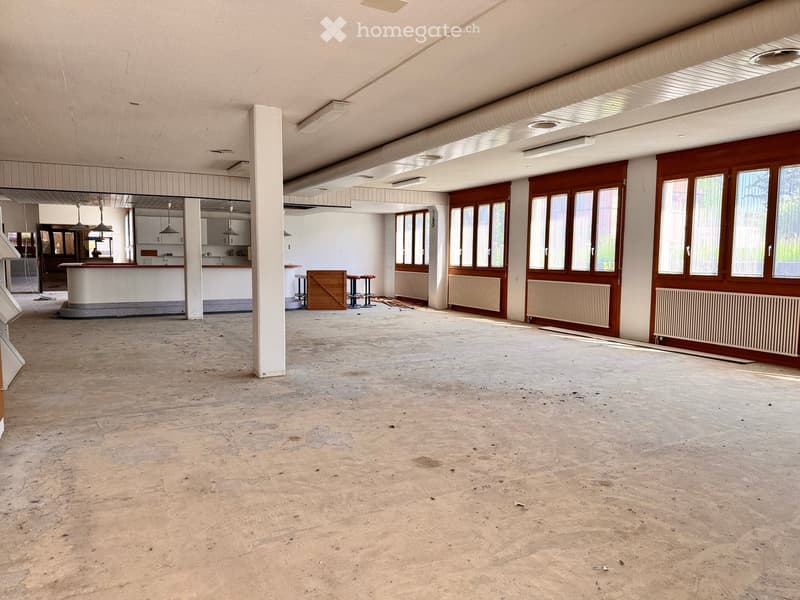 large open room, wooden door, large windows, white counters, no furniture