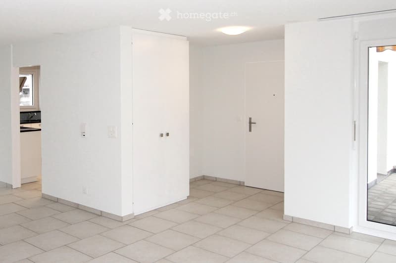 Empty room with white walls, tiled floor, and a large mirrored door. No furniture or equipment is present.