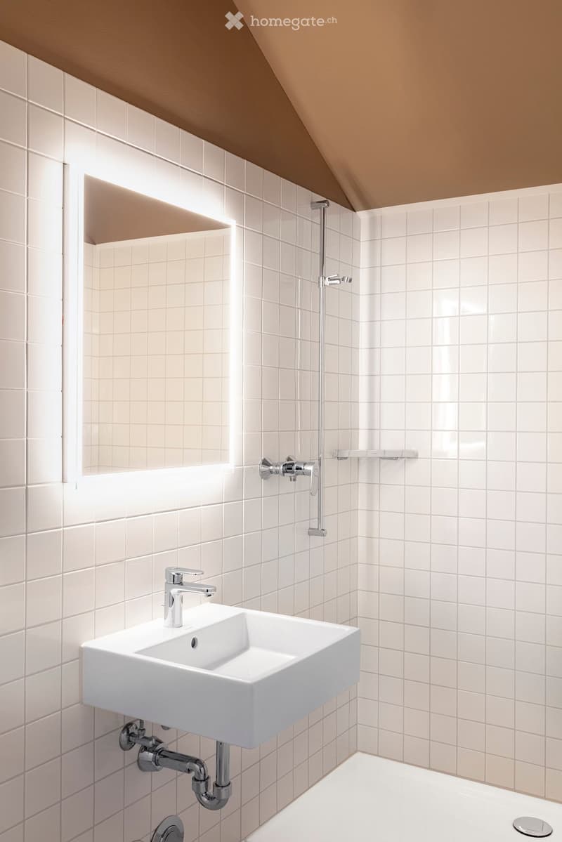 white bathroom with modern fixtures, shower head, wall-mounted soap dispenser, illuminated mirror, square bathtub, pedestal sink, and shower enclosure