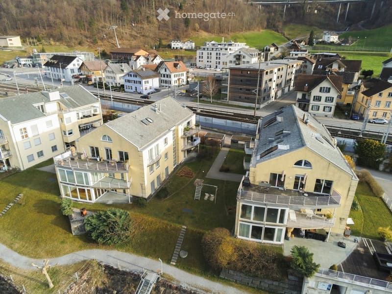 Aerial view of a residential area with multiple houses, balconies, and surrounding greenery.