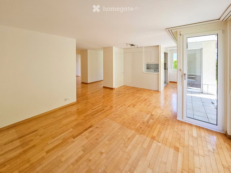 Empty room with wooden flooring, white walls, and a sliding glass door leading to a balcony area.