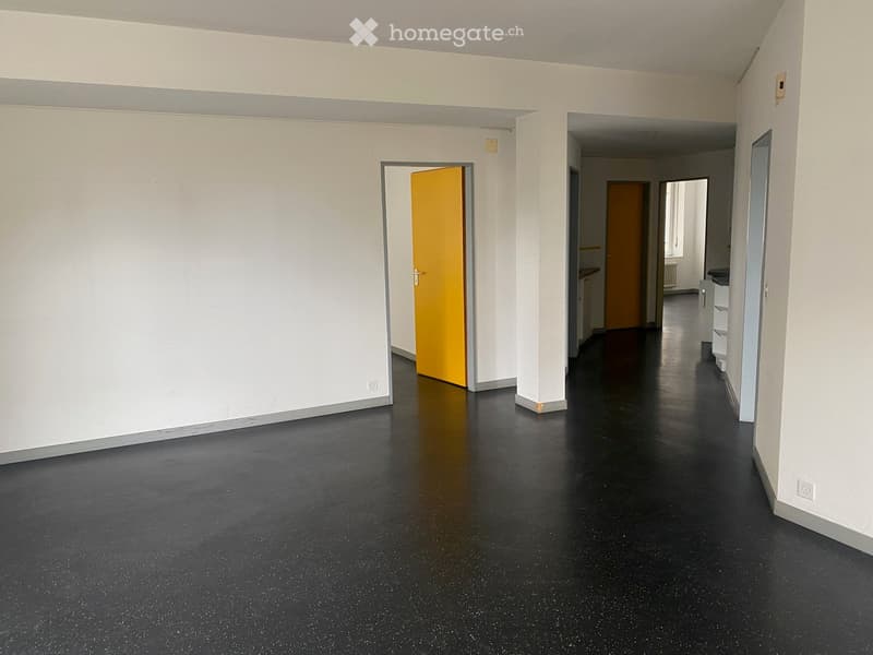 Empty hallway with black speckled floor, white walls, and doors leading to other rooms.