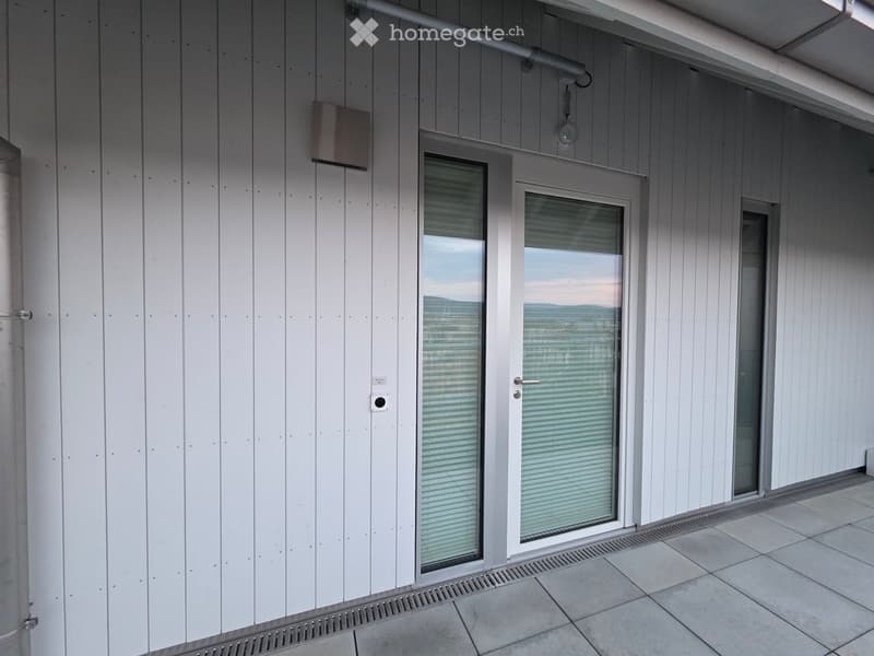 Balcony with white wooden panel walls, large glass sliding doors, tiled floor, and a view of the landscape.