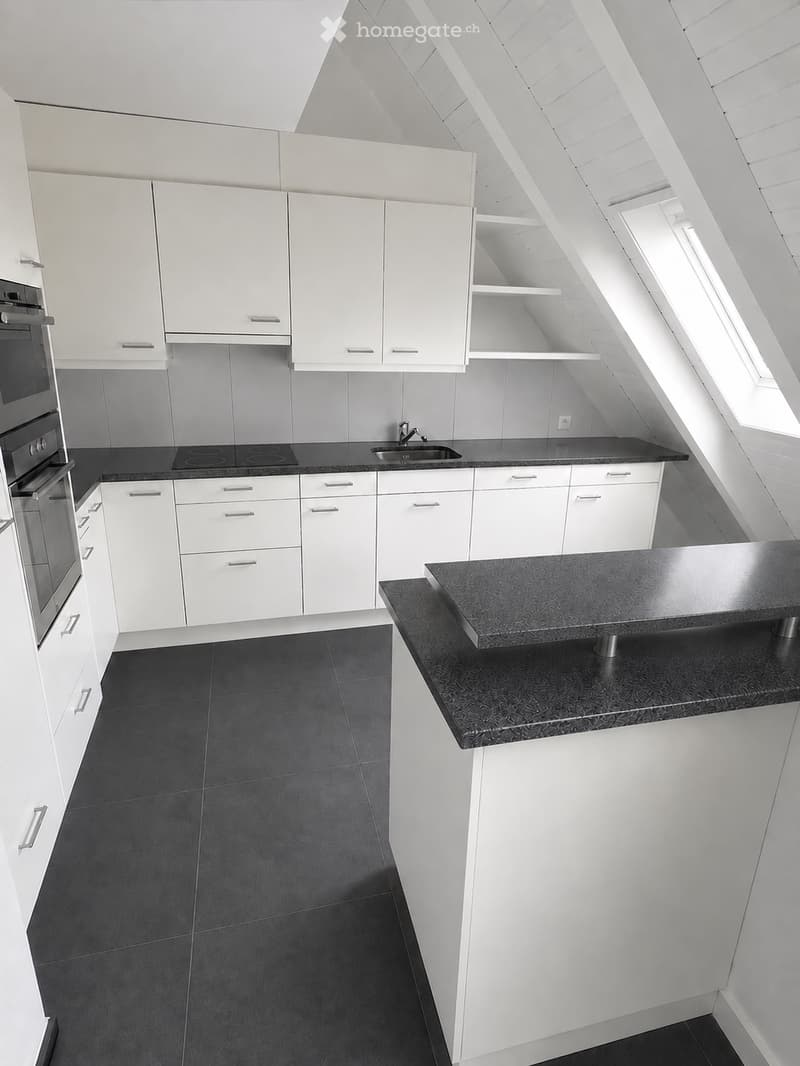 Modern kitchen with white cabinets, black countertops, and a sleek design. Features include an oven, sink, and faucet.