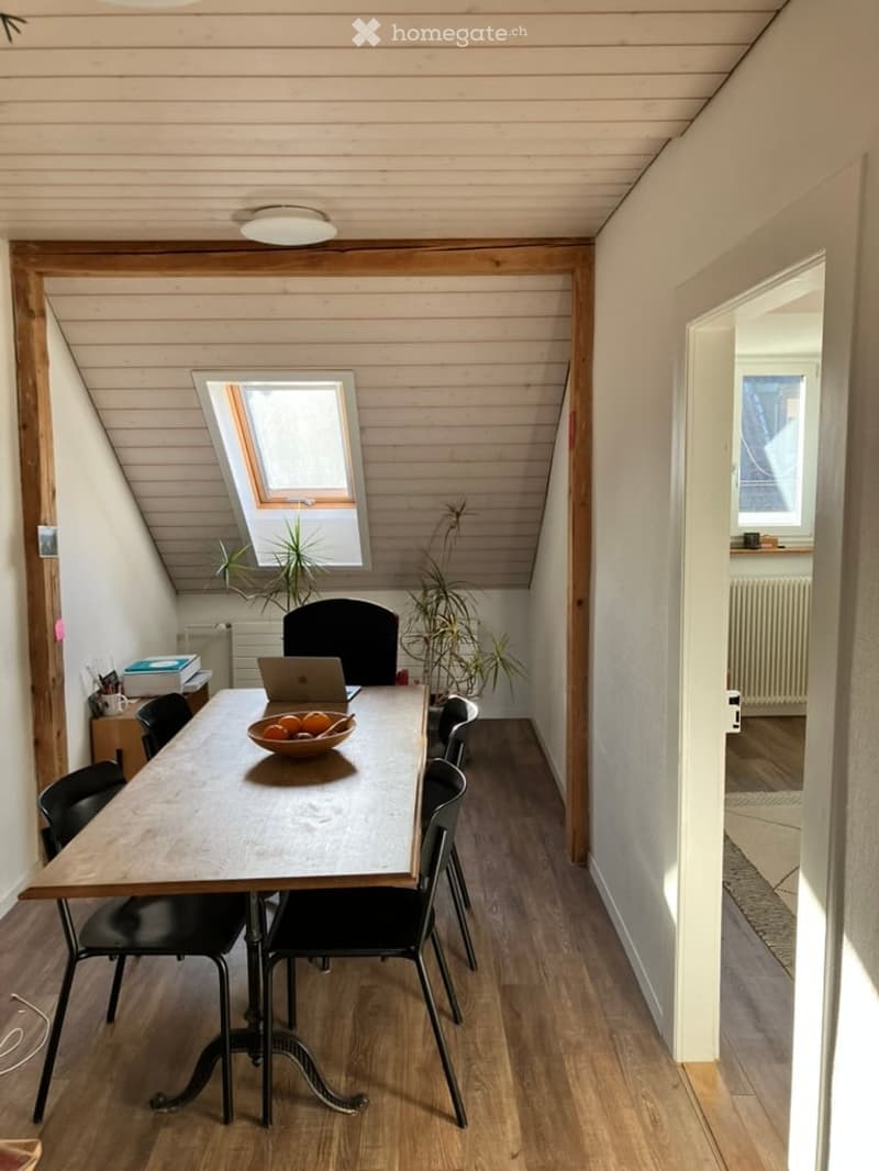 dining table with chairs, laptop on the table, plants on the corner, wooden flooring, small table with objects
