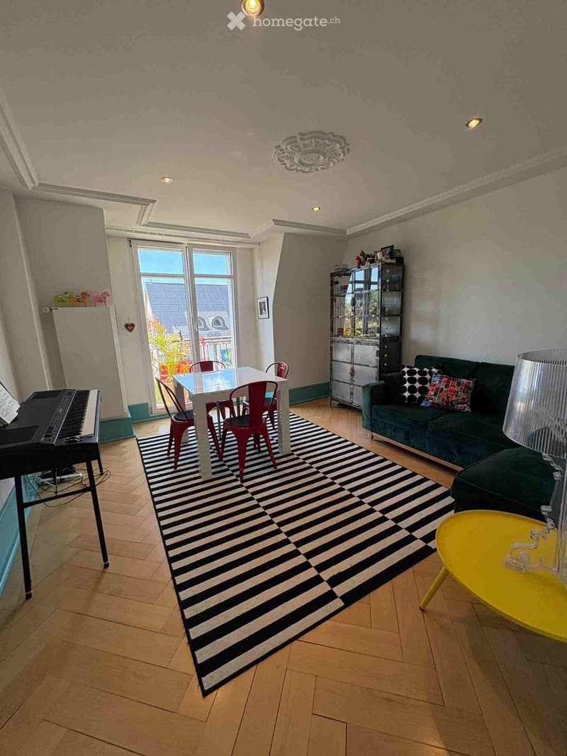 Living room with a green sofa, white dining table with red chairs, black piano, yellow coffee table, and a black and white striped rug.