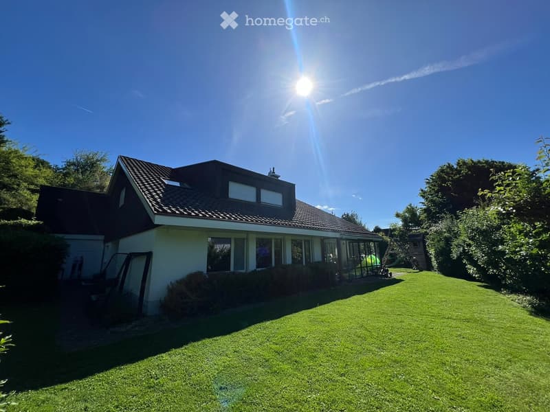 Two-story house with a tiled roof, large windows, and a well-maintained lawn in the front yard.