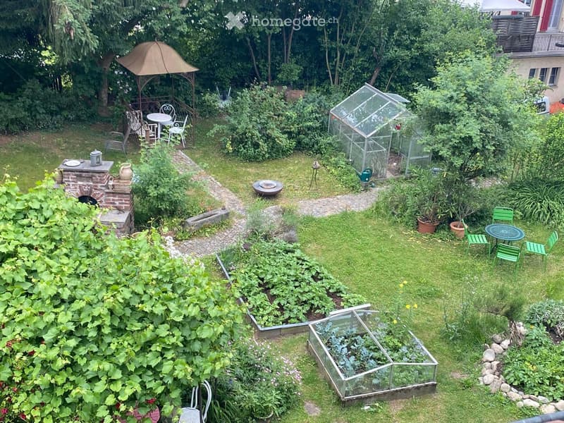 Garden with a gazebo, patio furniture, raised beds, greenhouse, and various plants.