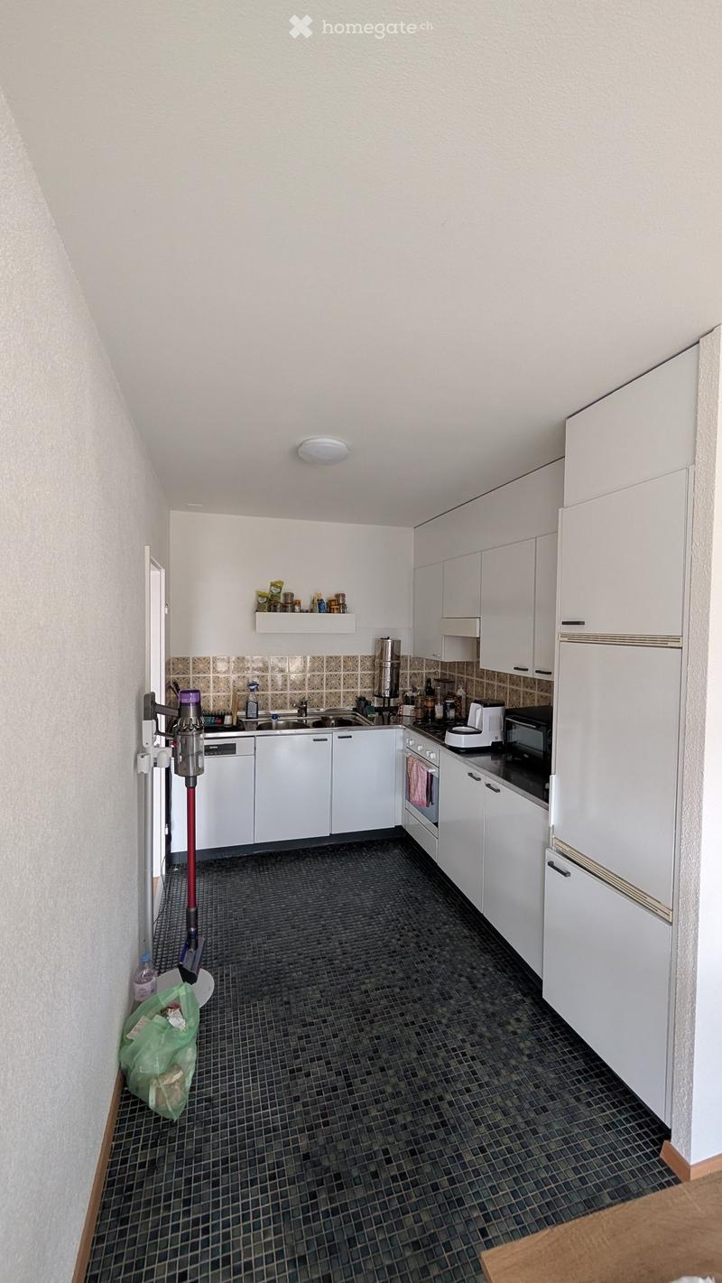 Modern kitchen with white cabinets, stainless steel appliances, and a dark tiled floor. Includes a refrigerator, oven, dishwasher, sink, microwave, toaster, and various kitchen items on the counter.