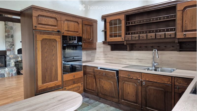 Wooden kitchen with cabinets, sink, faucet, oven, and a round table.