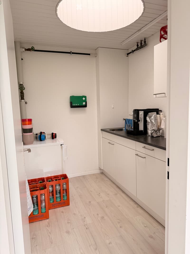 modern kitchen, white cabinets, black countertop, built-in sink, espresso machine, stack of bowls, orange crates, first aid kit