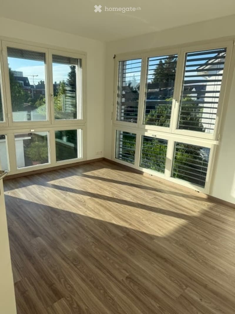 Empty room with wooden flooring and large windows allowing natural light to fill the space. No furniture or equipment present.