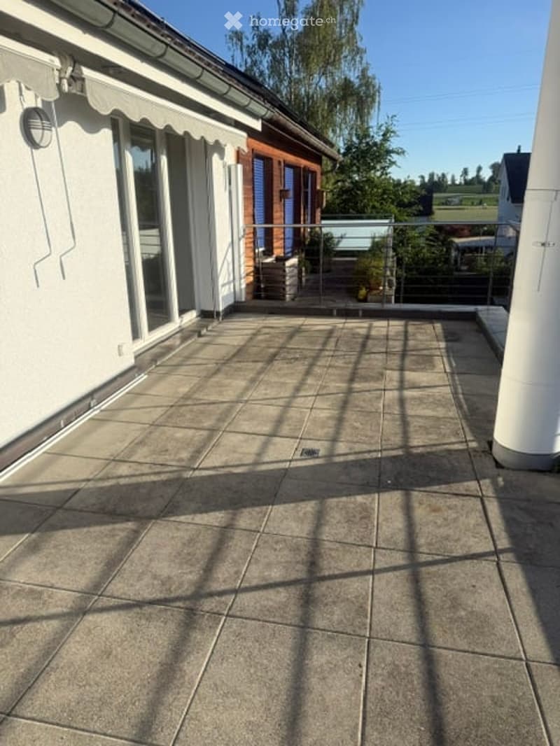 Balcony with tiled floor, metal railing, and a view of a green landscape.
