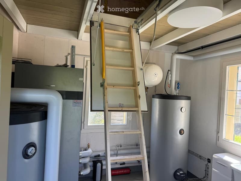 Utility room with water heaters, ladder, pipes, and a light fixture.