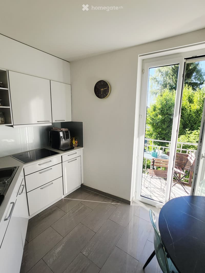 Modern kitchen with white cabinets, stainless steel appliances, and a sliding glass door leading to a balcony.