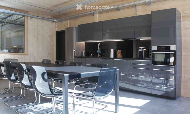 modern kitchen with a large table, stainless steel appliances, wooden wall, and a large window