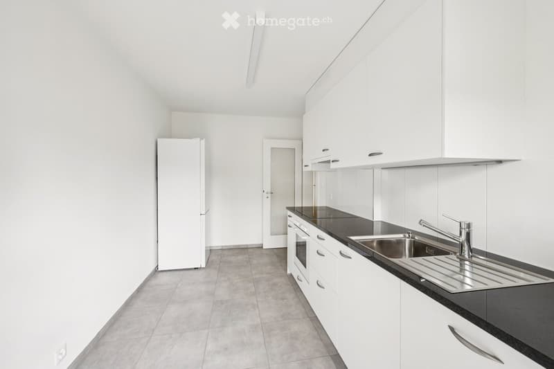 Modern kitchen with white cabinets, black countertops, stainless steel sink, and built-in appliances.