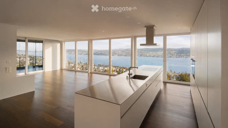 Kitchen. Modern kitchen with white cabinets, stainless steel island, large windows offering a scenic view of a lake and cityscape.