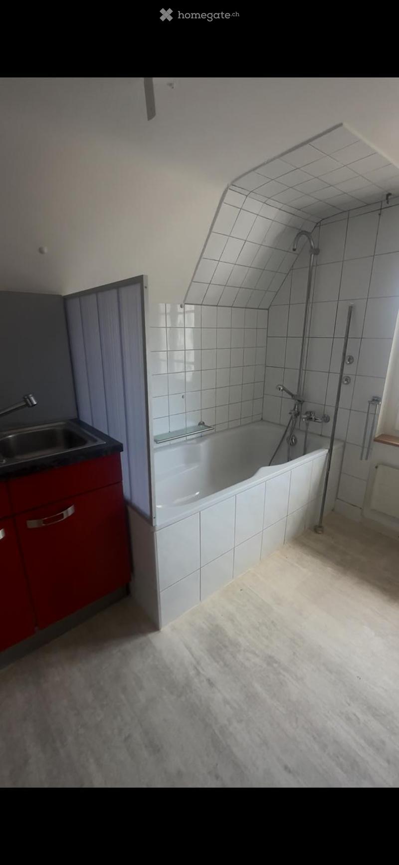Bathroom with a white tiled bathtub, a red cabinet, a sink, and a faucet.