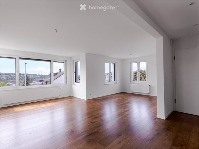 Empty room with wooden flooring, white walls, multiple windows, and radiators.