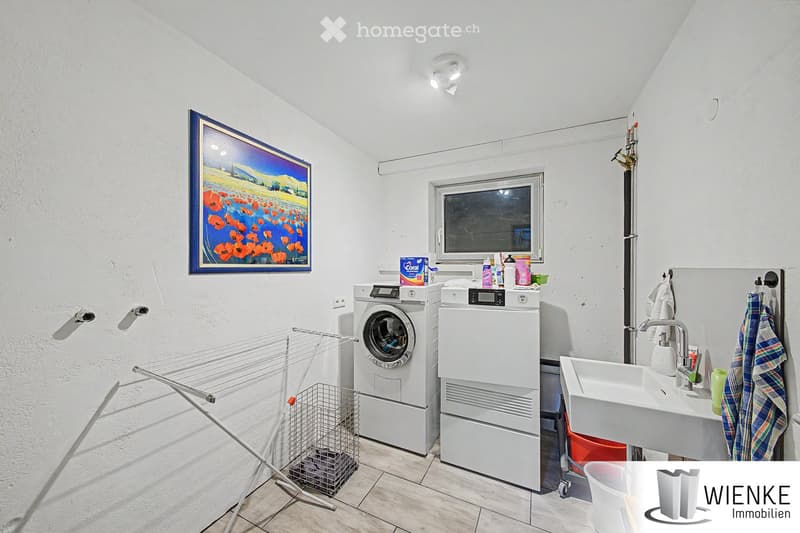 Bathroom with white walls, tiled floor, washing machine, dishwasher, sink, and a drying rack.