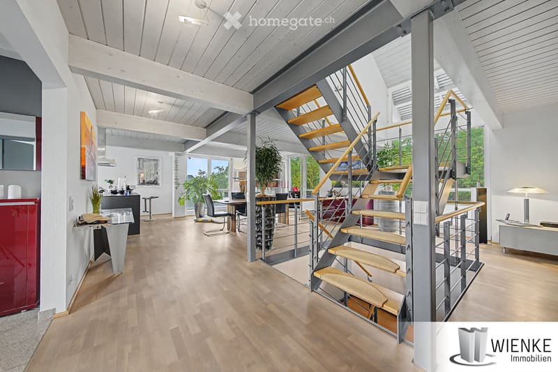 Modern, open-concept living space with wooden flooring, a staircase with metal railings, and contemporary furniture including chairs, tables, and a cabinet.