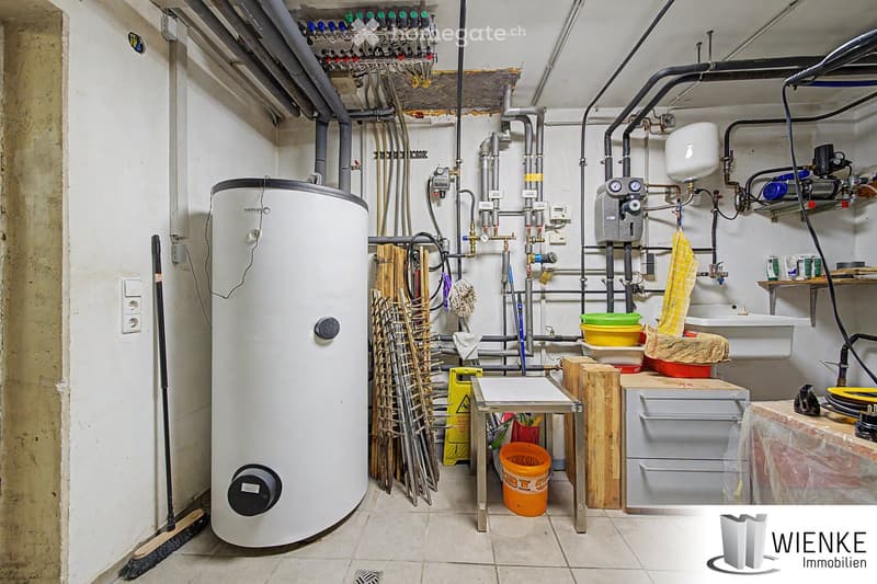 Utility room with water heater, sink, wooden stool, shelves, and cleaning supplies.