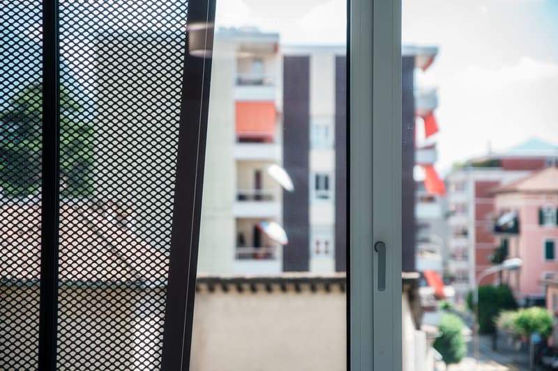 A view from a balcony or terrace showing a cityscape with modern apartment buildings and greenery.