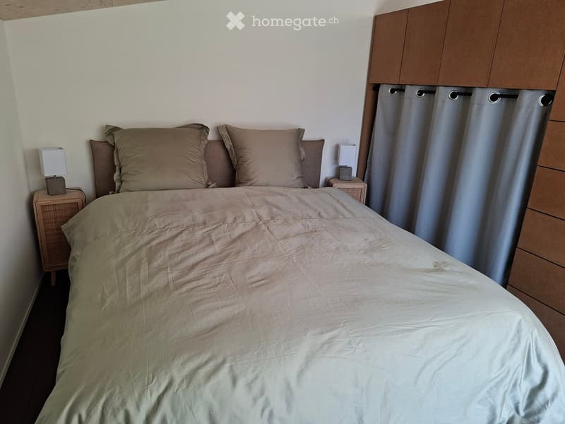 Bedroom with a neatly made bed, pillows, and bedside tables with lamps.