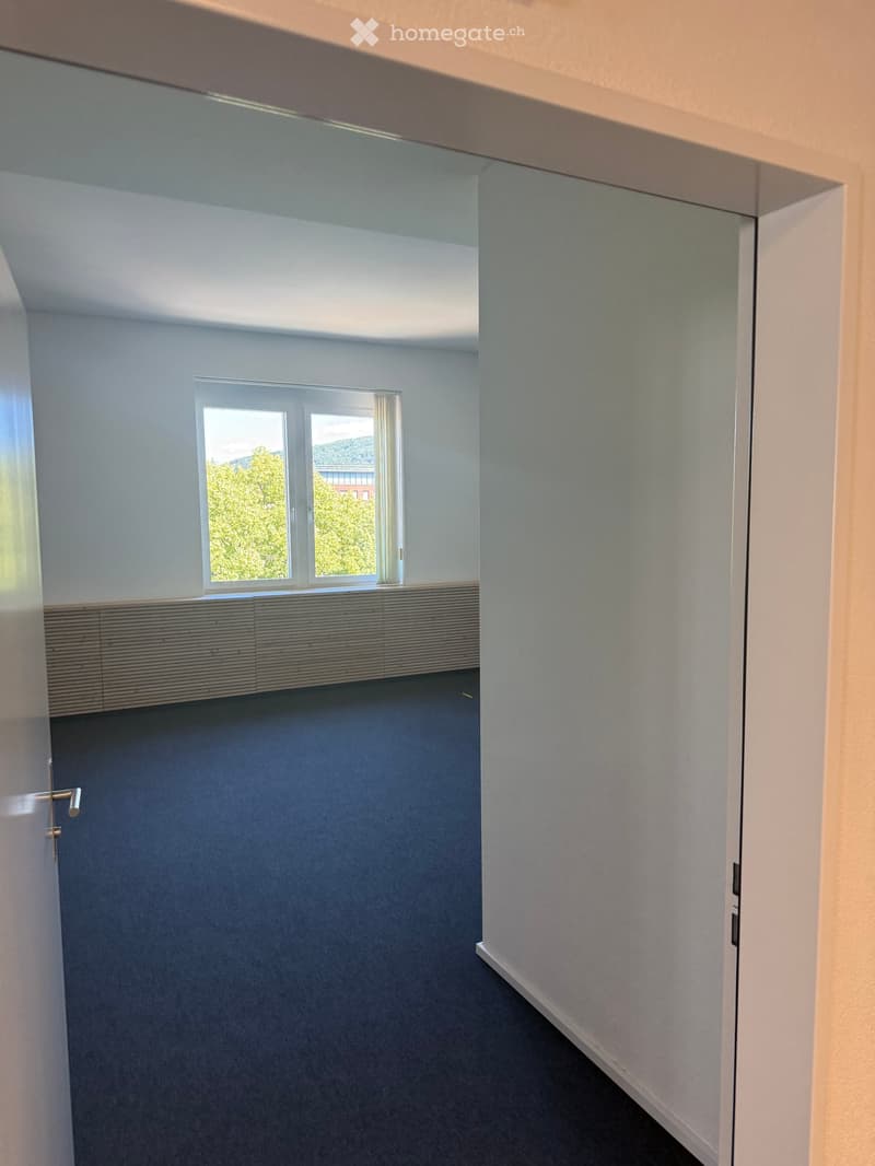 Empty room with grey carpeted floor, white walls, and a large window with blinds. No furniture or equipment present.