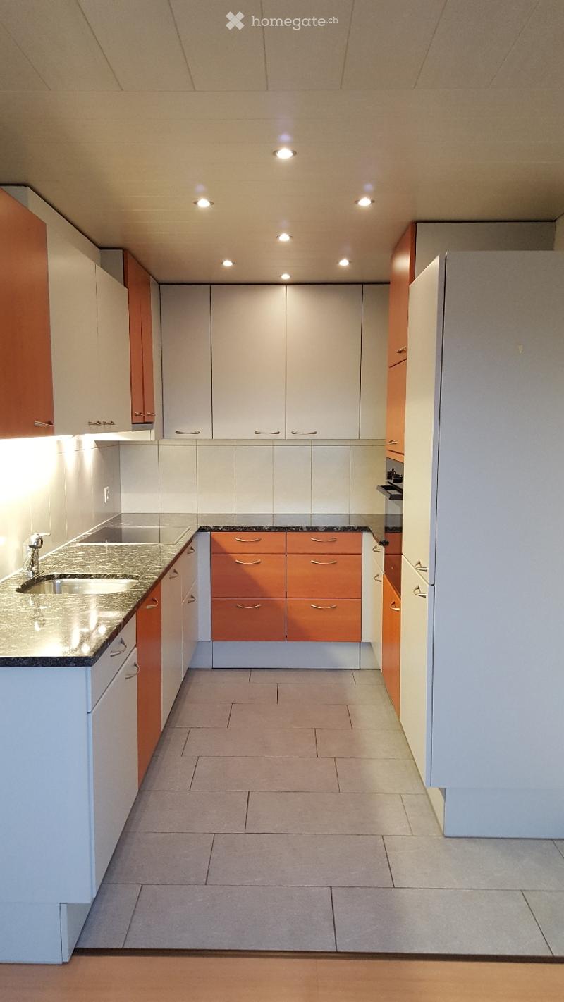 Modern kitchen with white and orange cabinets, granite countertops, and a stainless steel sink.