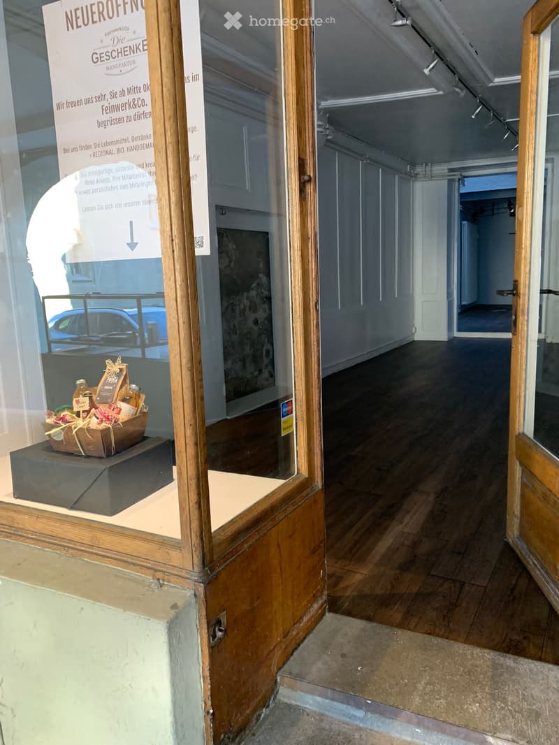 Empty room with wooden flooring and white walls, visible through an open doorway. No furniture or equipment present.