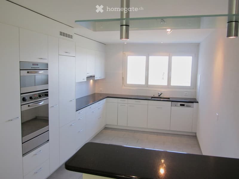 Modern kitchen with white cabinets, stainless steel appliances, and a black countertop.