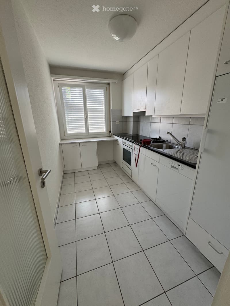Kitchen. Modern kitchen with white cabinets, tiled floor, and stainless steel appliances including a sink, oven, and dishwasher.