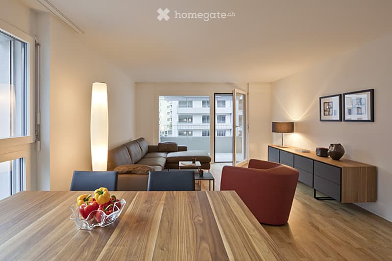 Modern living room with a sectional sofa, coffee table, dining table, chairs, and a balcony view.
