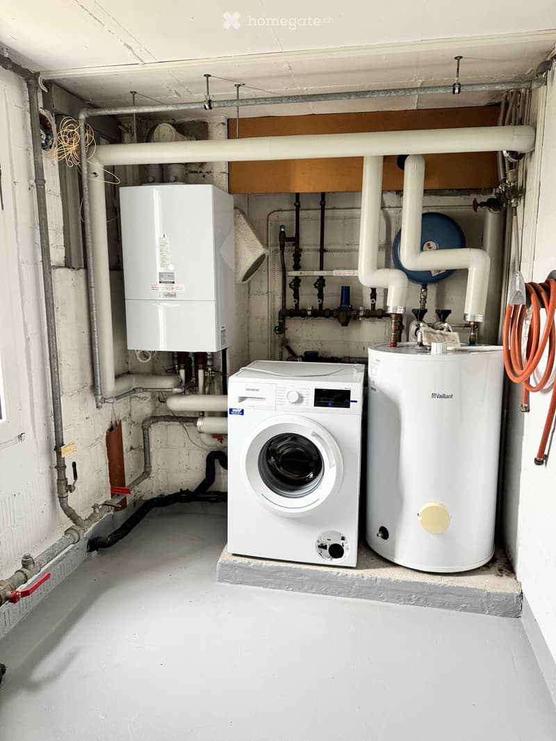 Utility room with a white Siemens washing machine, Vaillant water heater, and various pipes and valves.