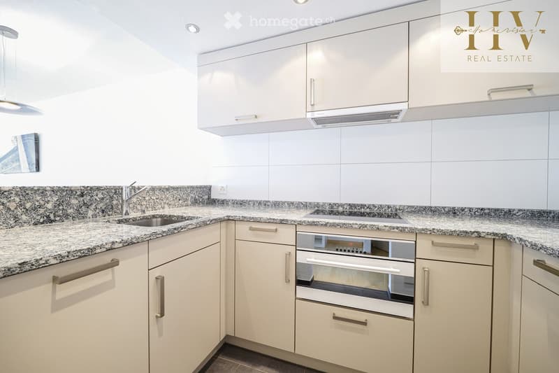 Modern kitchen with white cabinets, granite countertops, stainless steel sink, and built-in oven.