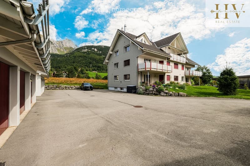 Two-story house with grey siding, white trim, balconies, and a scenic mountain view in the background.