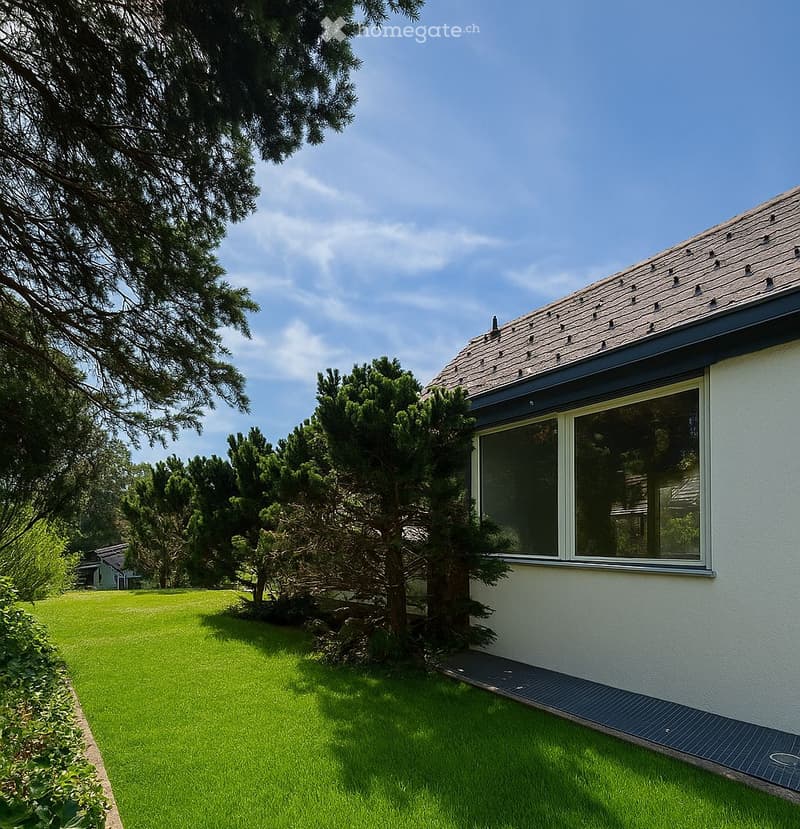 A well-maintained garden with a neatly trimmed lawn, surrounded by trees and shrubs, adjacent to a modern house with large windows and a sloped roof.