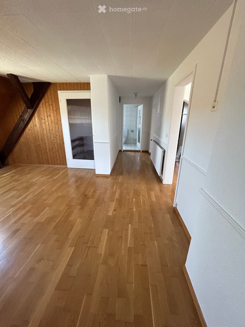 Empty hallway with wooden flooring, white walls, and several doors leading to different rooms.