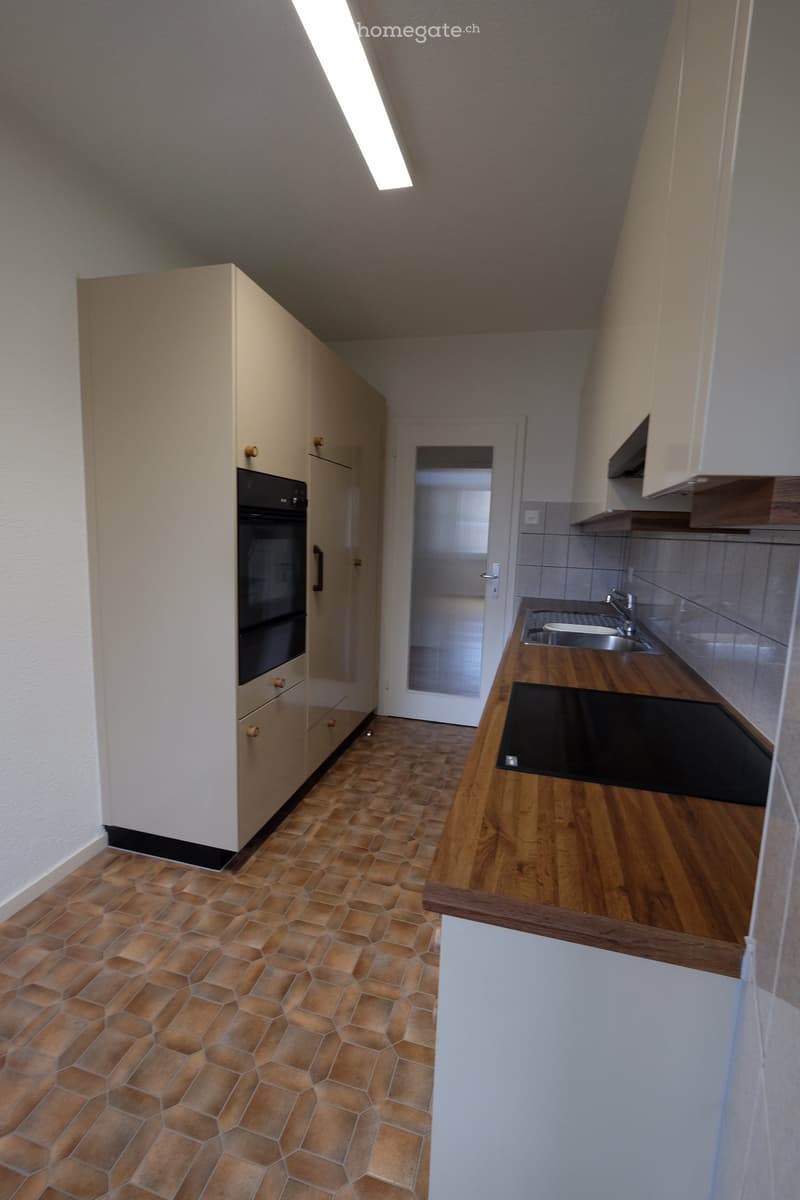 Modern kitchen with wooden countertops, tiled floor, built-in oven, and stainless steel sink.