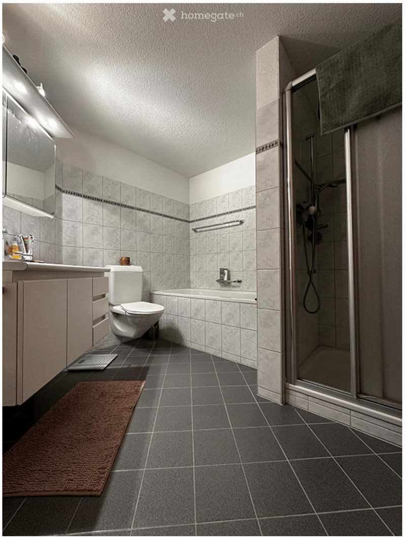 Modern bathroom with grey tiled floor, white tiled walls, a toilet, a bathtub, a shower, a mirror, and a bathroom cabinet.