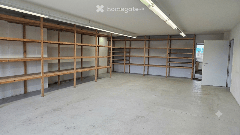 Empty room with wooden shelving units against the walls and a concrete floor.