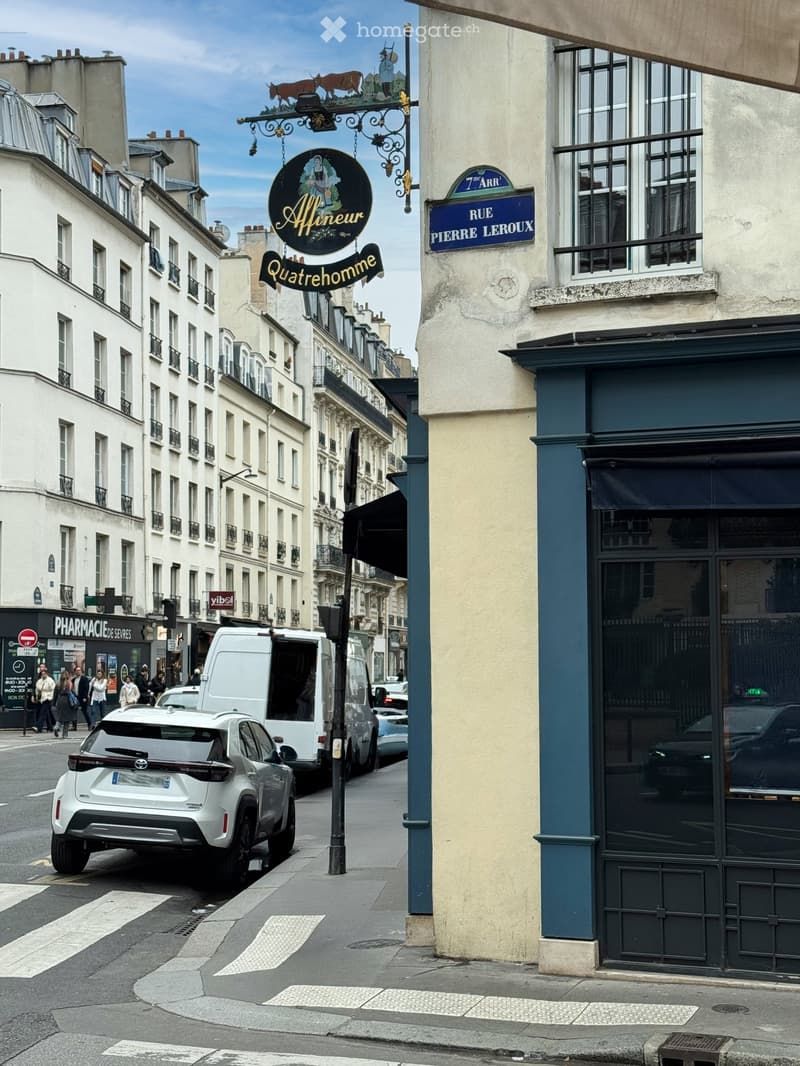Street scene with vehicles, shopfronts, and pedestrians