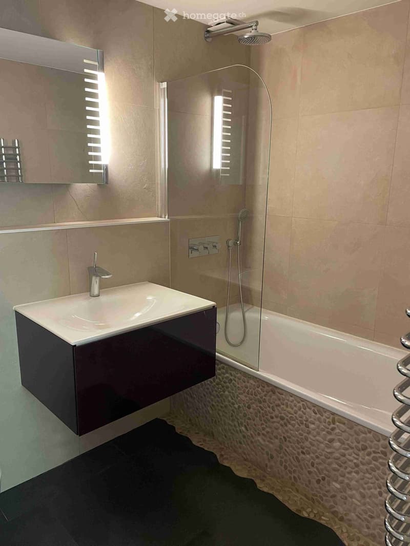 white bathtub, silver faucet, black cabinet, glass shower enclosure