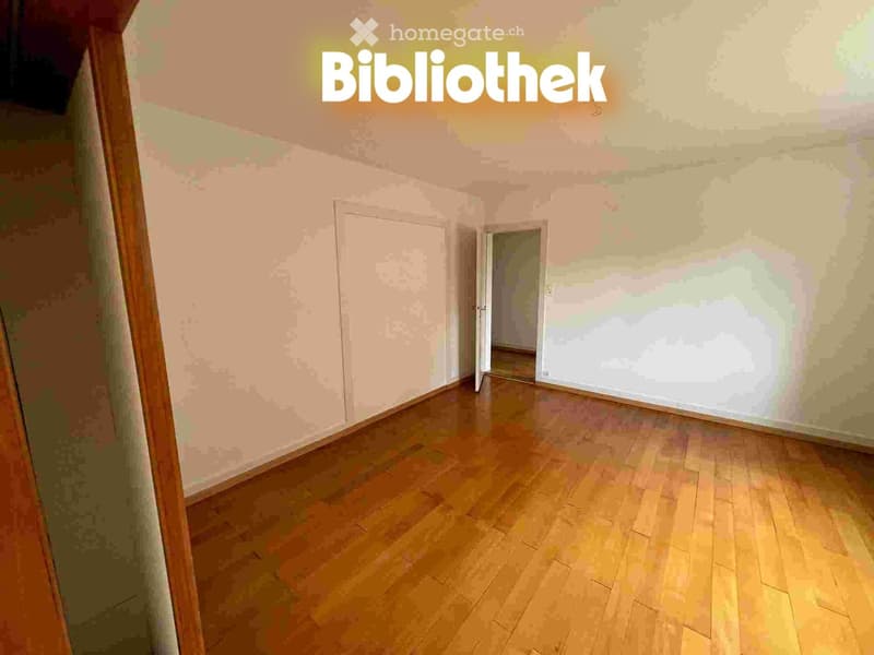 Empty room with wooden flooring and light-colored walls, featuring an open doorway leading to another space.